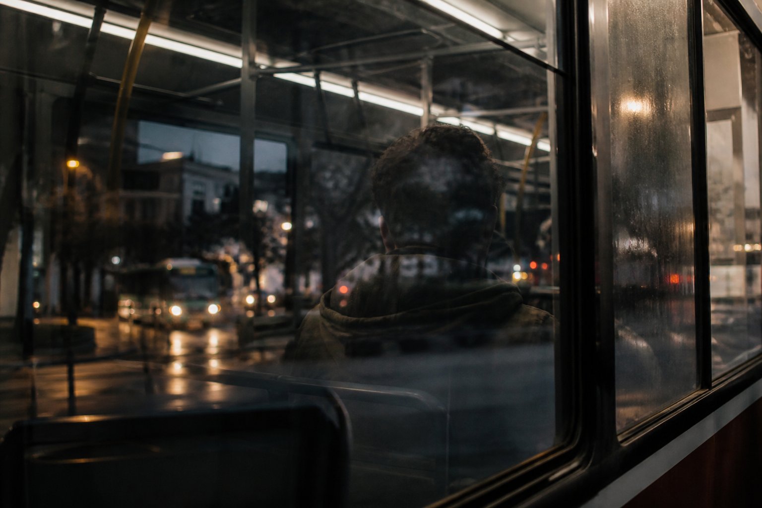 Reflejos superpuestos en la ventana de un bus de Santiago al anochecer